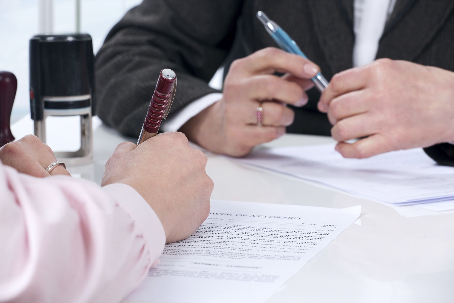 A man and a woman are signing a document at a table