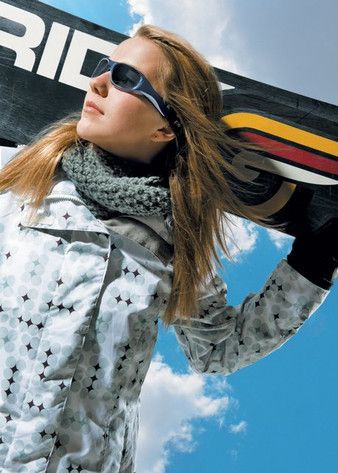 A woman wearing sunglasses is holding a snowboard that says rid on it