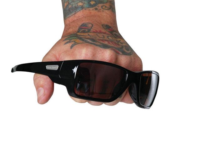 A tattooed hand is holding a pair of sunglasses
