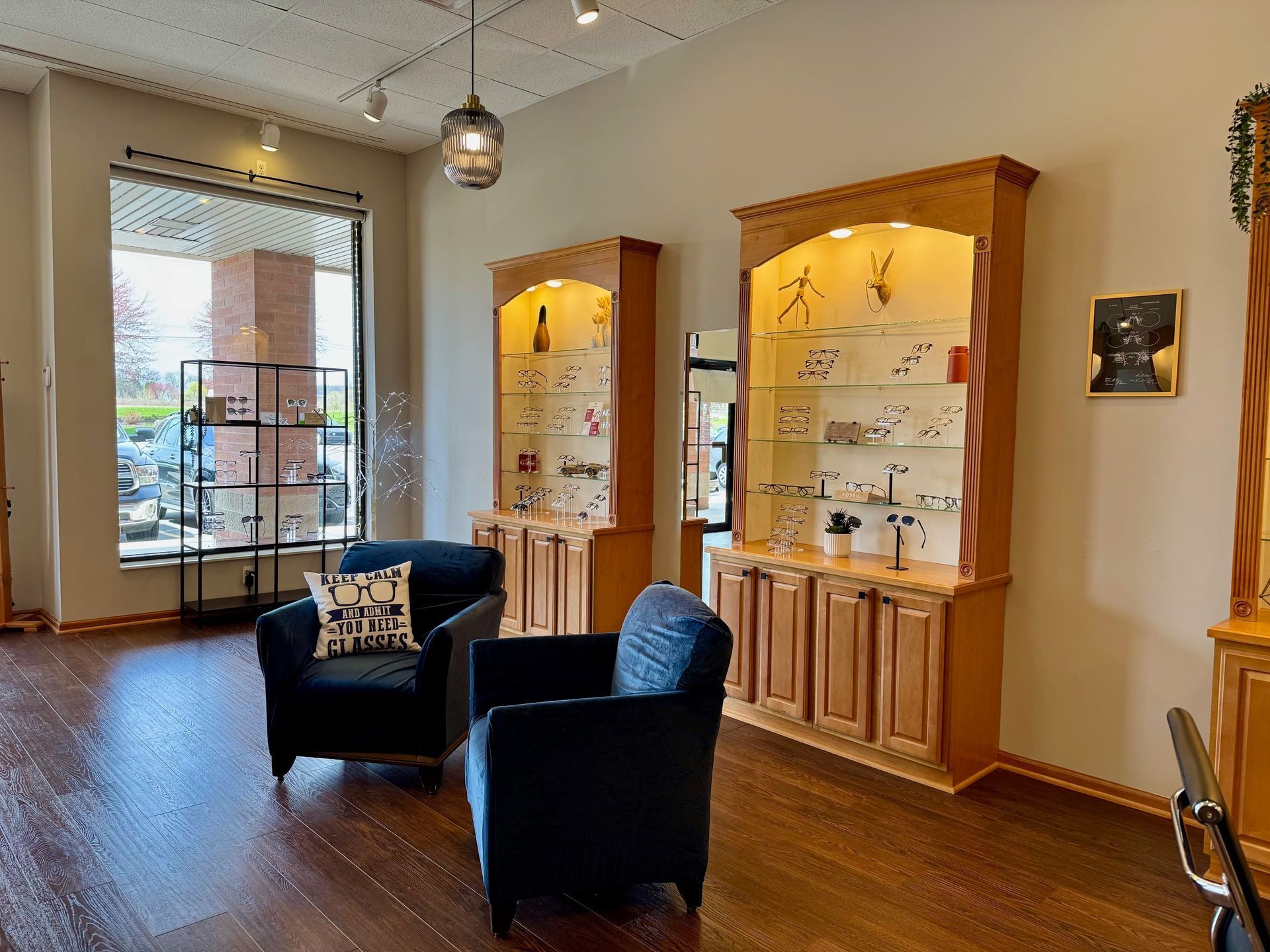 A living room with two chairs and a shelf with glasses on it.