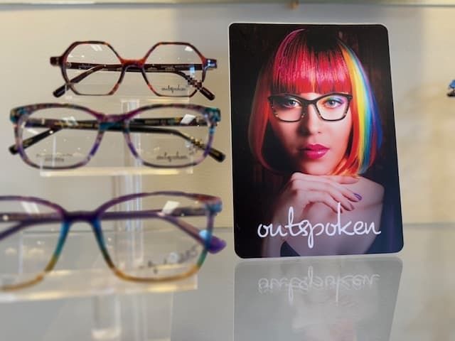A picture of a woman wearing glasses next to a card that says outspoken