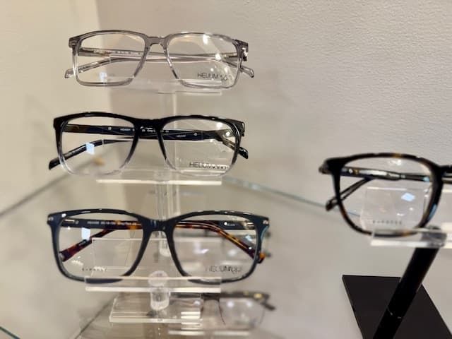 Several pairs of glasses are displayed on a glass shelf