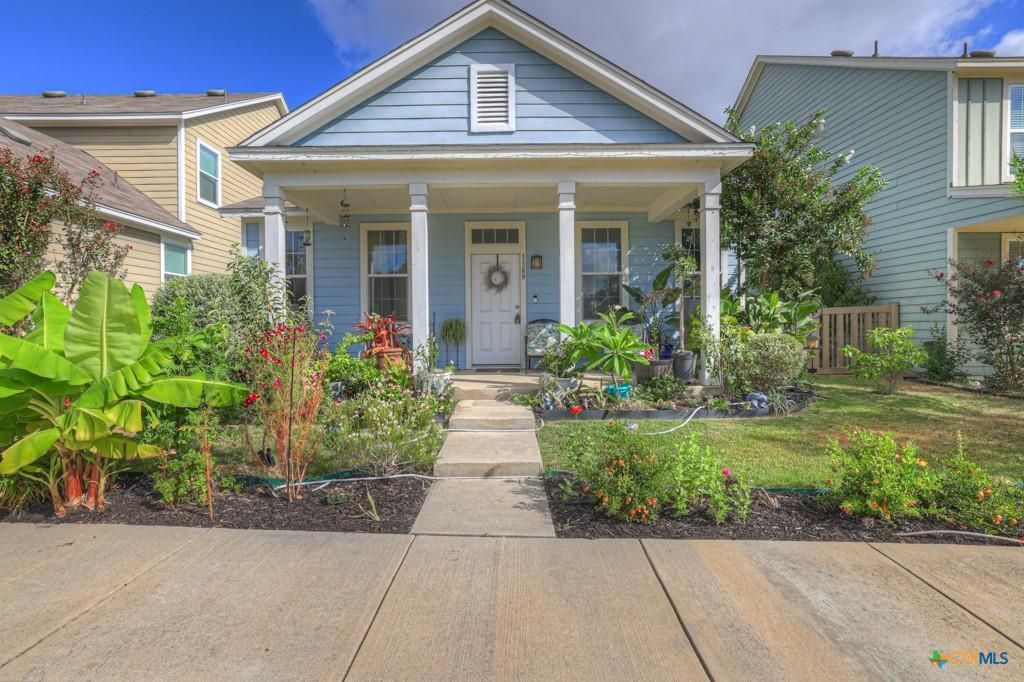 Blue house with white columns, front porch, and garden.