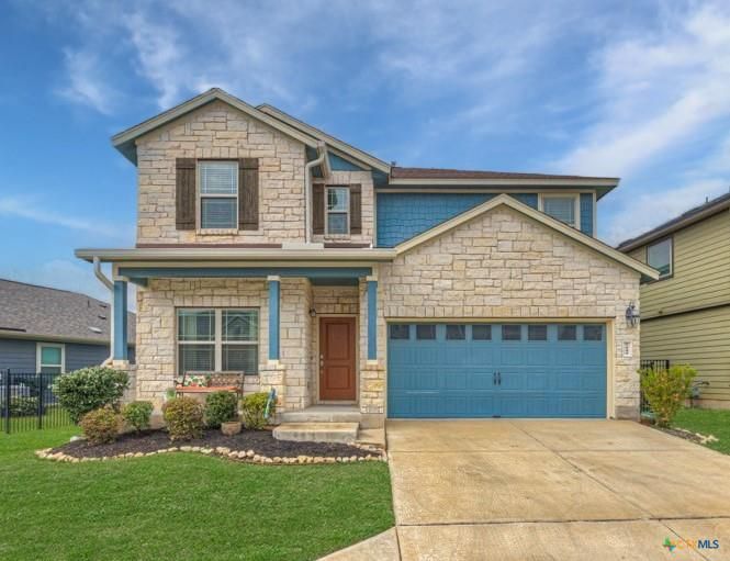 Two-story house with stone facade, blue accents, and a two-car garage under a blue sky.