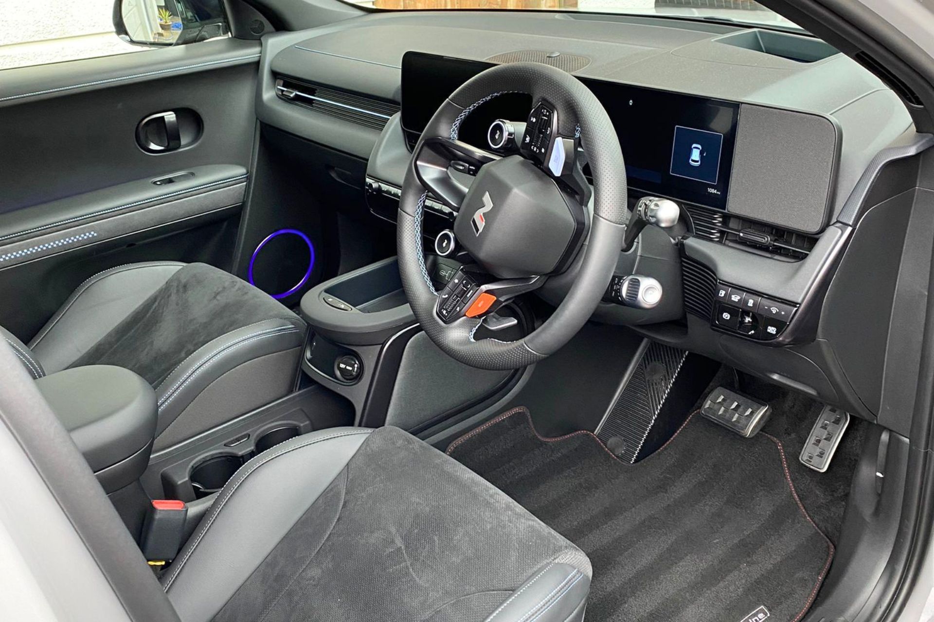 Modern car interior with black seats, steering wheel, dashboard screen, and center console