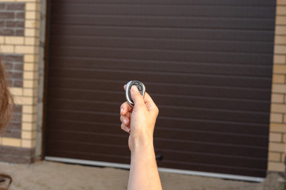 Custom Garage Door — Hand With Remote Control Opens For Garage Door in Signal Hill, CA