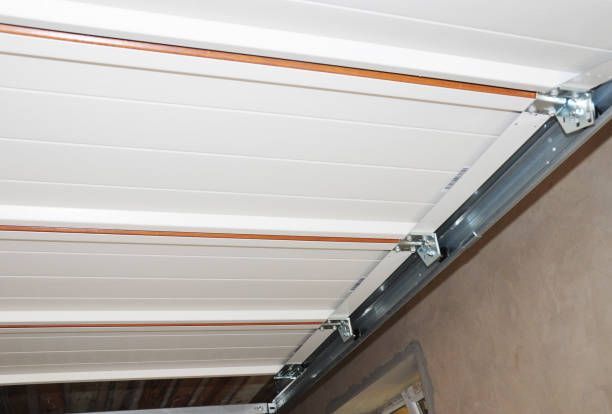 White sectional garage door with metal tracks and hinges installed on ceiling.