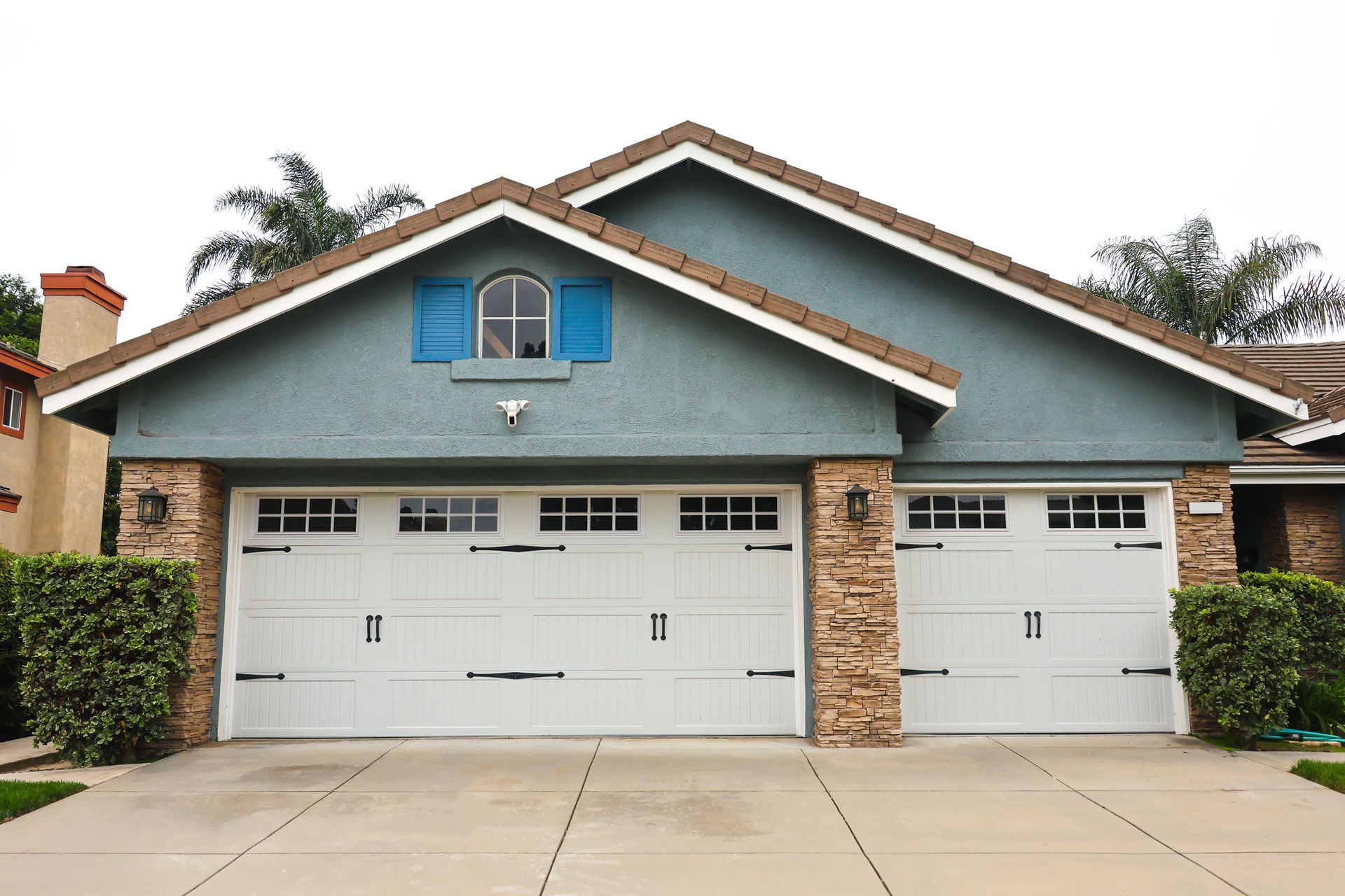 Modern white garage doors with decorative windows and black hardware.