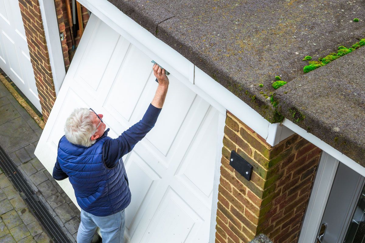 Senior man cleaning dirty garage door at home