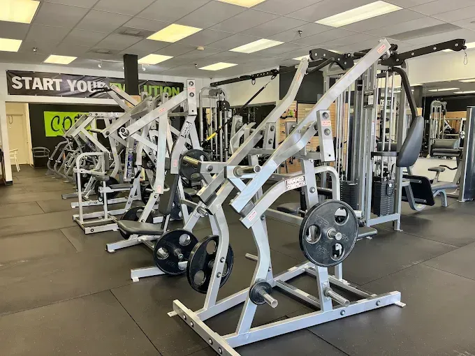 Gym interior with various weight machines and equipment.