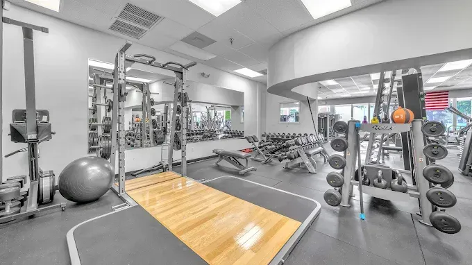 Gym interior with weight racks, benches, and exercise equipment.