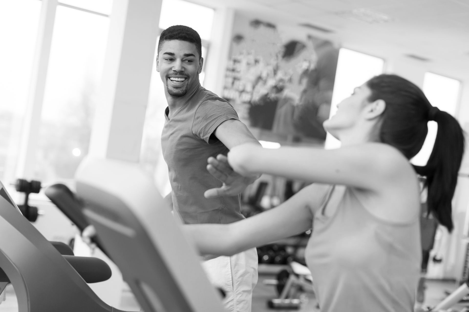 A man and a woman are riding treadmills in a gym.