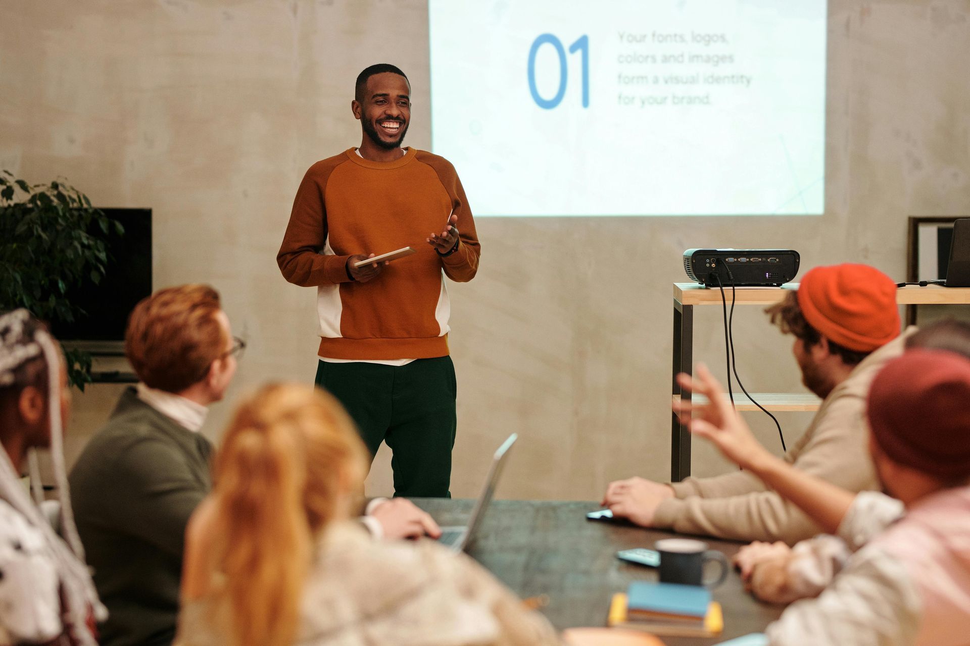 A man is giving a presentation to a group of people sitting around a table.