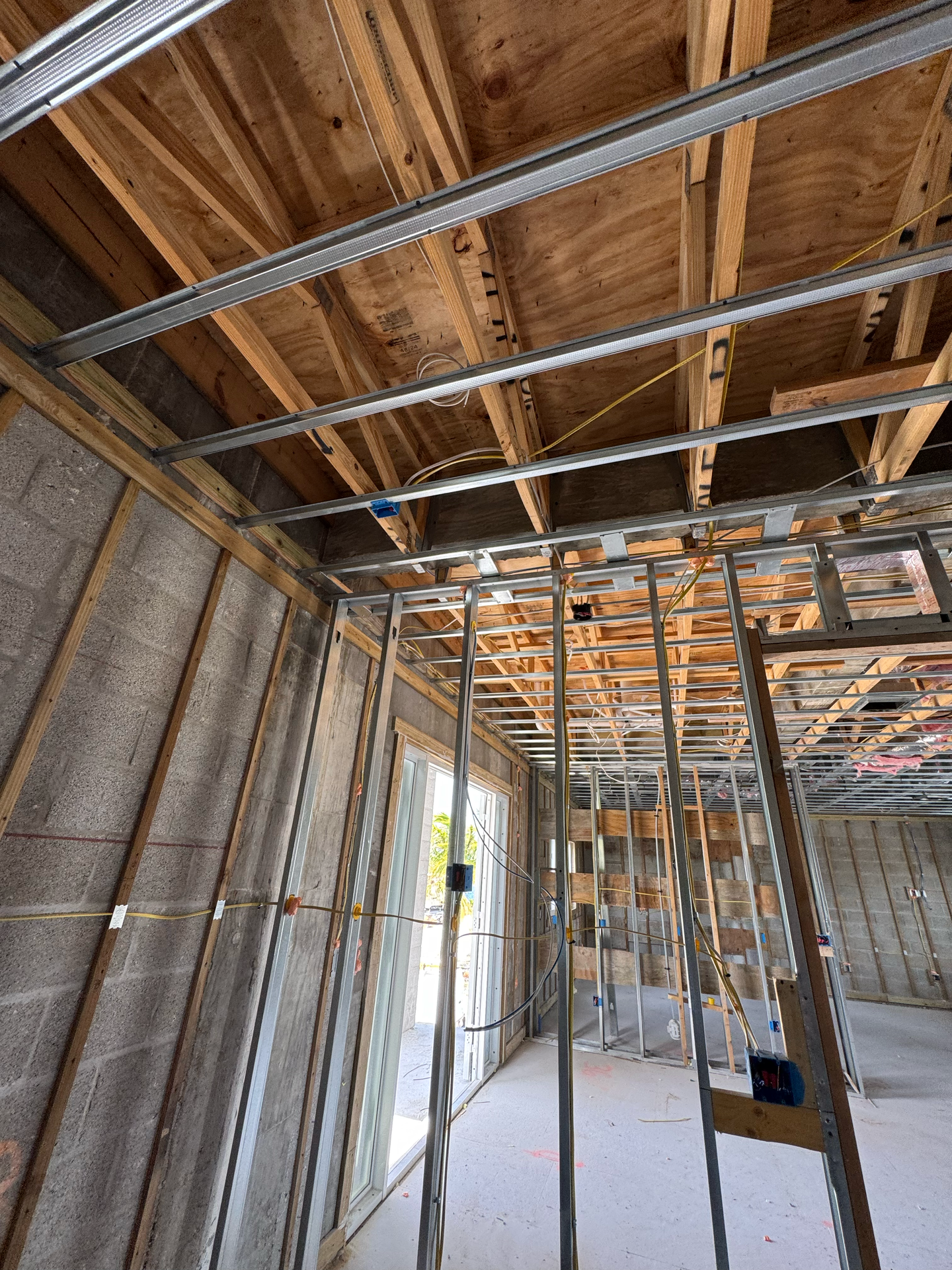 Interior of a building under construction, showing metal studs and unfinished ceiling with wood beams.