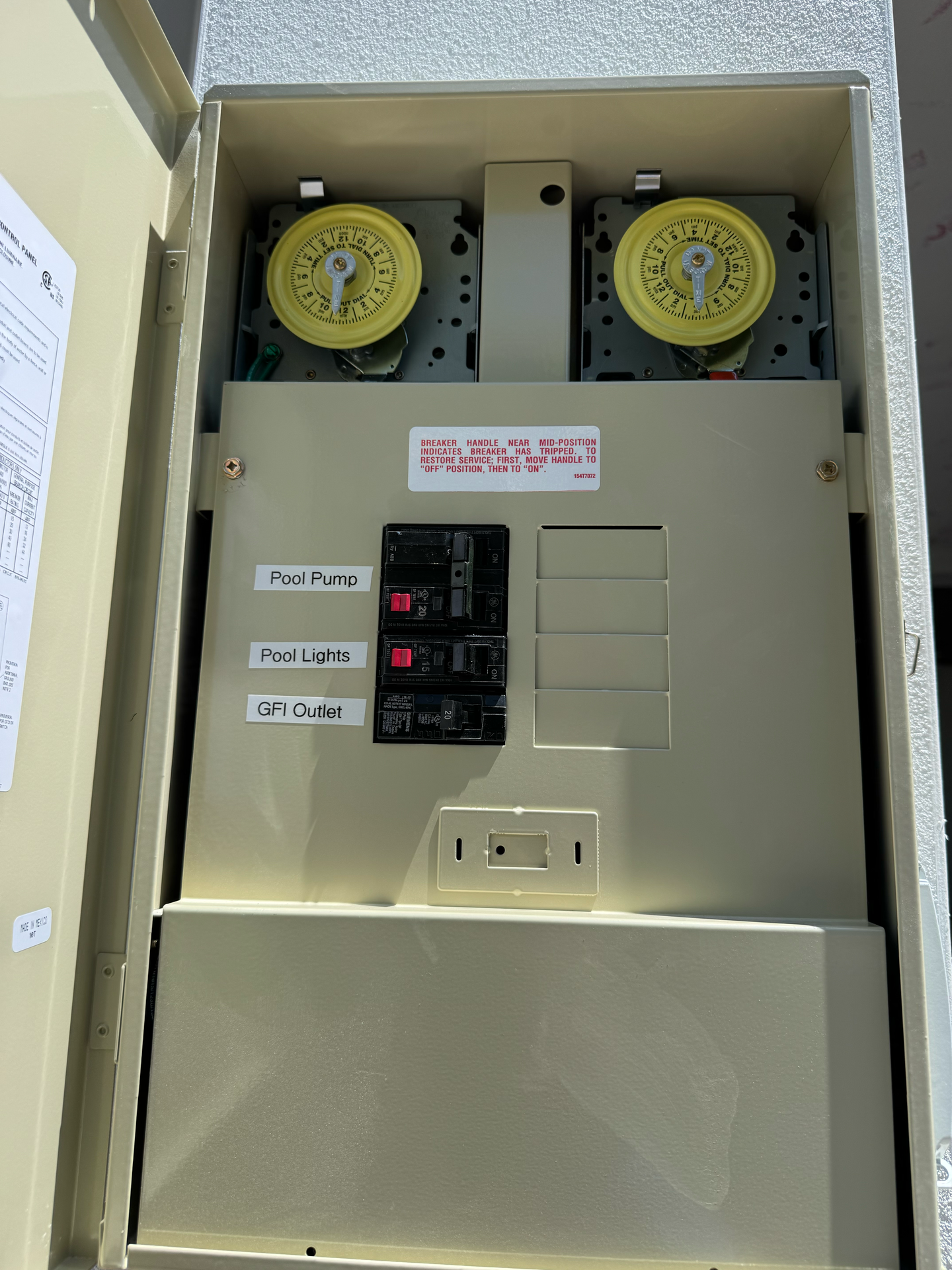 Pool equipment timer control panel with two timers, circuit breakers, and an outlet.
