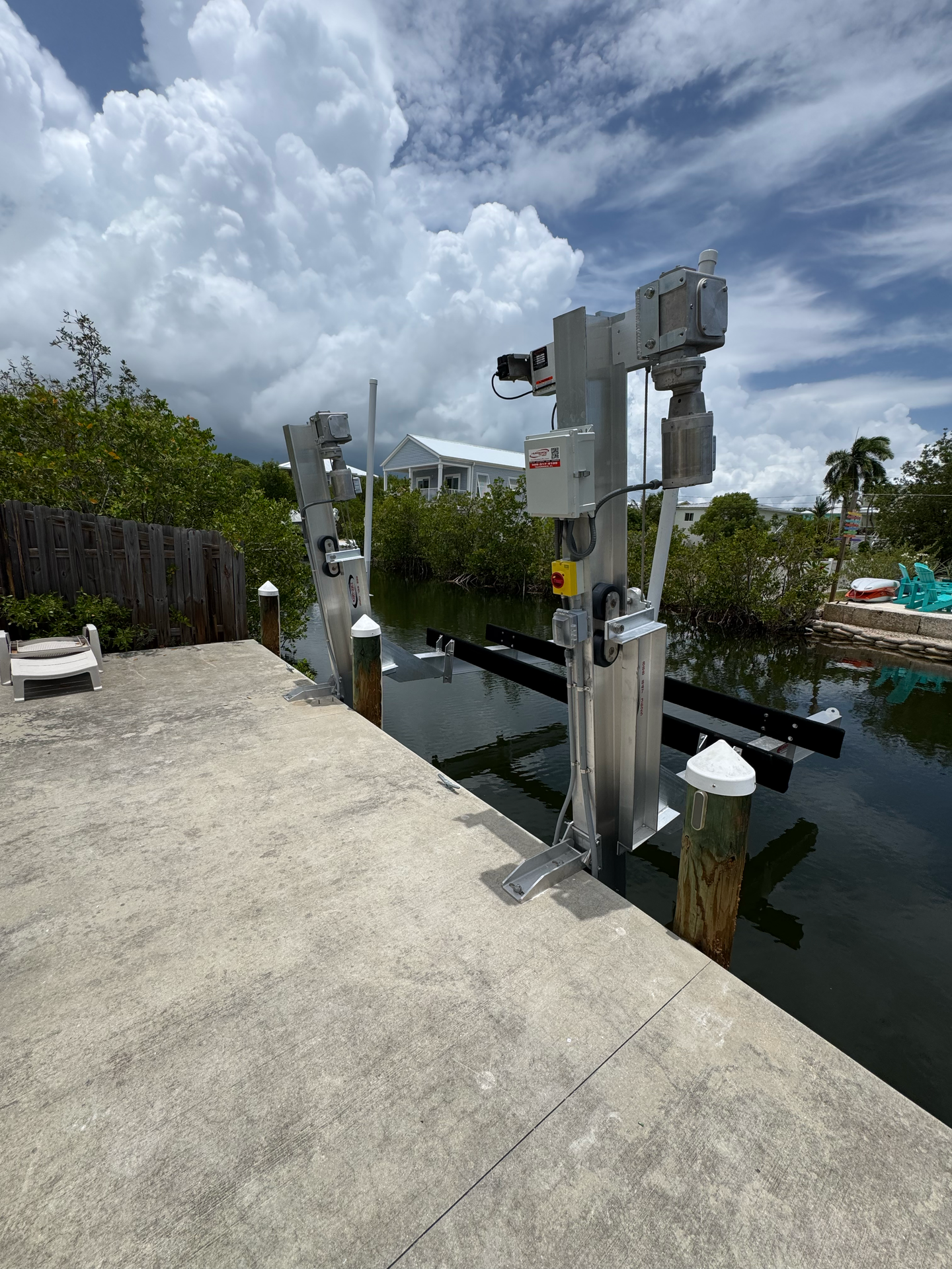Boat lift on a concrete dock, overlooking a waterway with mangroves.