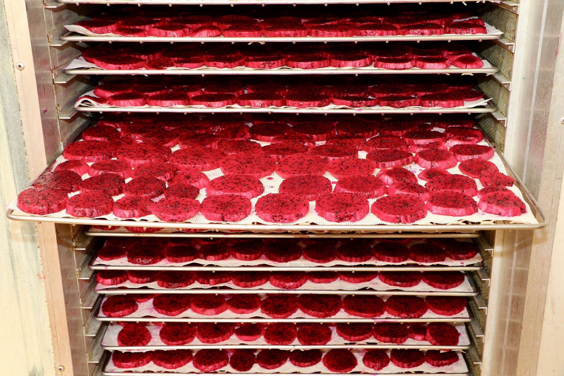A bunch of red cupcakes are sitting on a shelf in a refrigerator.