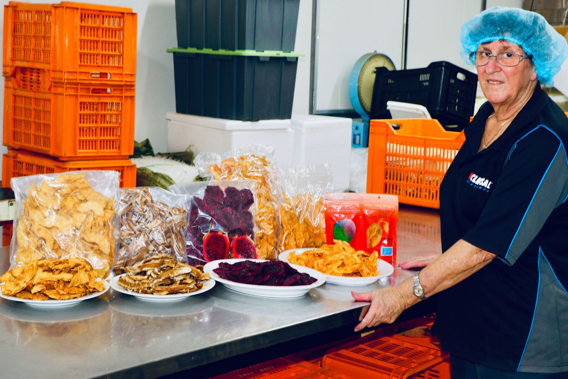A Woman is Standing in Front of a Table With Plates of Food on It — Mareeba Golden Dried Mangoes in Mareeba, QLD
