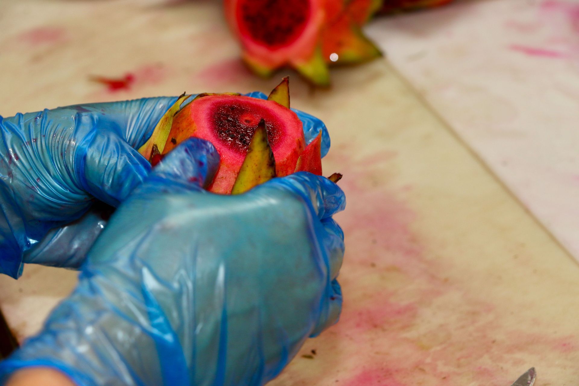 A Person Wearing Blue Gloves is Cutting a Dragon Fruit on a Table — Mareeba Golden Dried Mangoes in Mareeba, QLD