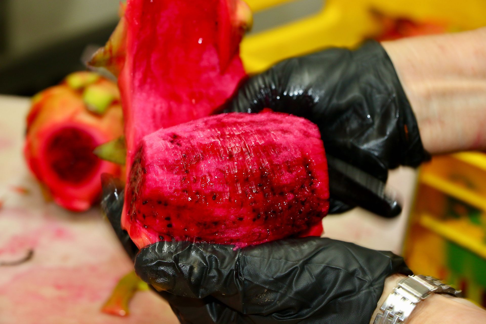 A Person Wearing Black Gloves is Holding a Piece of Red Fruit — Mareeba Golden Dried Mangoes in Mareeba, QLD