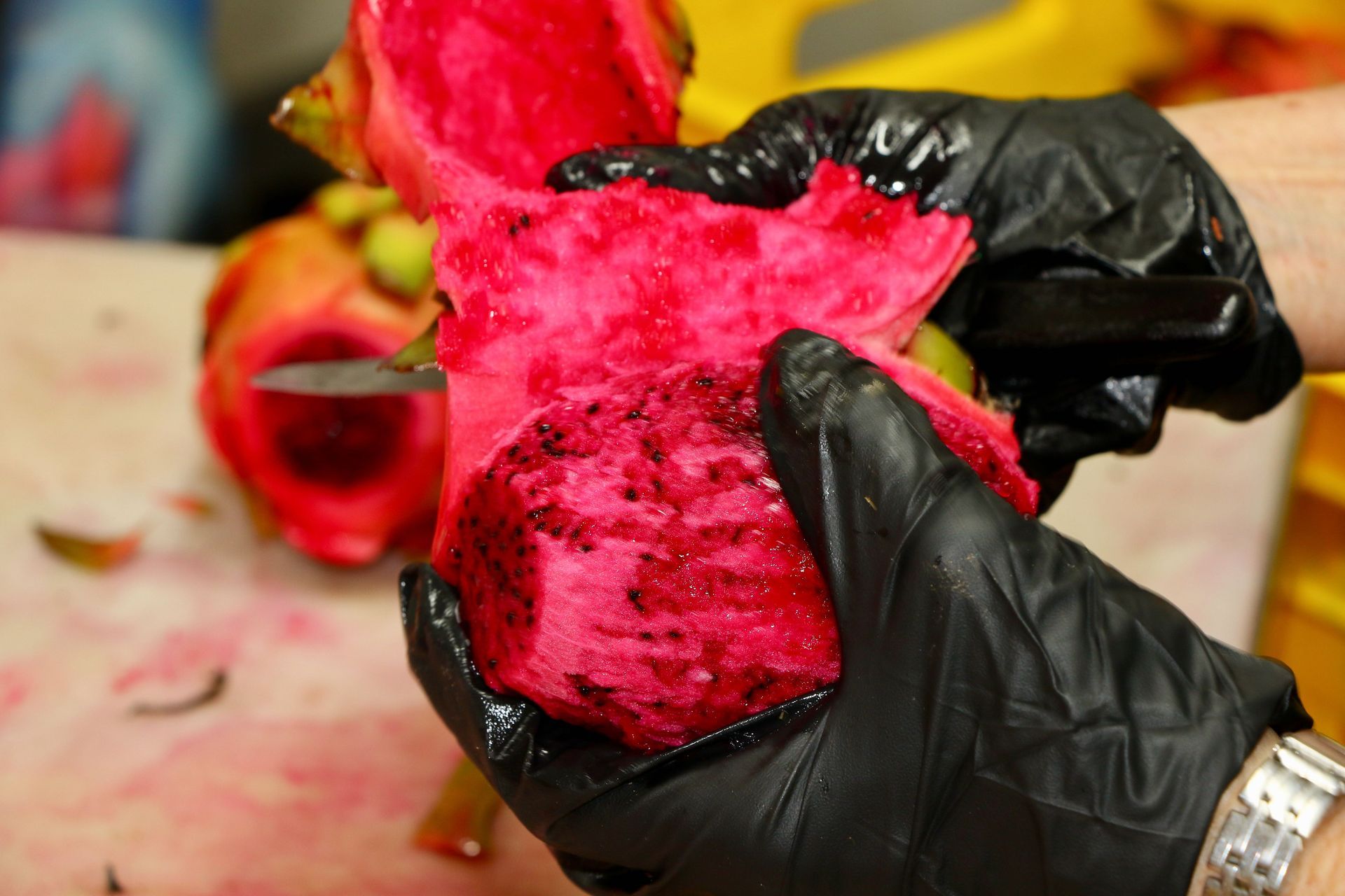 A Person Wearing Black Gloves is Holding a Red Fruit — Mareeba Golden Dried Mangoes in Mareeba, QLD