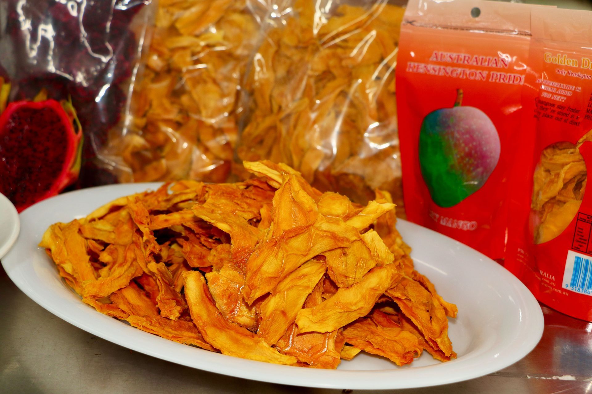 A White Plate Topped With Dried Fruit Next to a Bag of Dried Fruit — Mareeba Golden Dried Mangoes in Mareeba, QLD