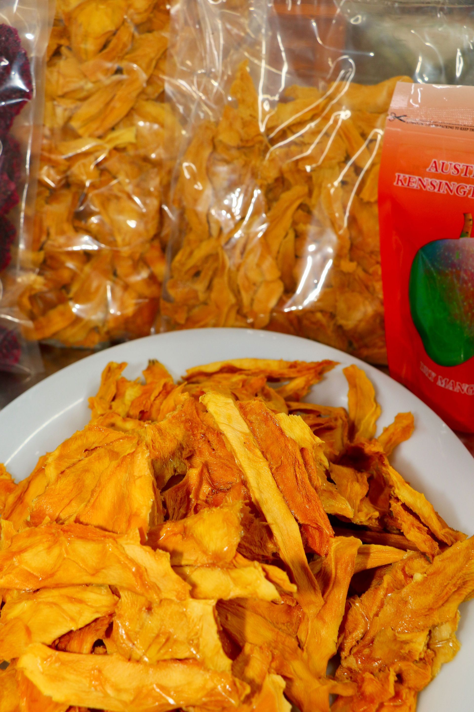 A Bag of Dried Mango Chips is Next to a Plate of Dried Mango Chips — Mareeba Golden Dried Mangoes in Mareeba, QLD