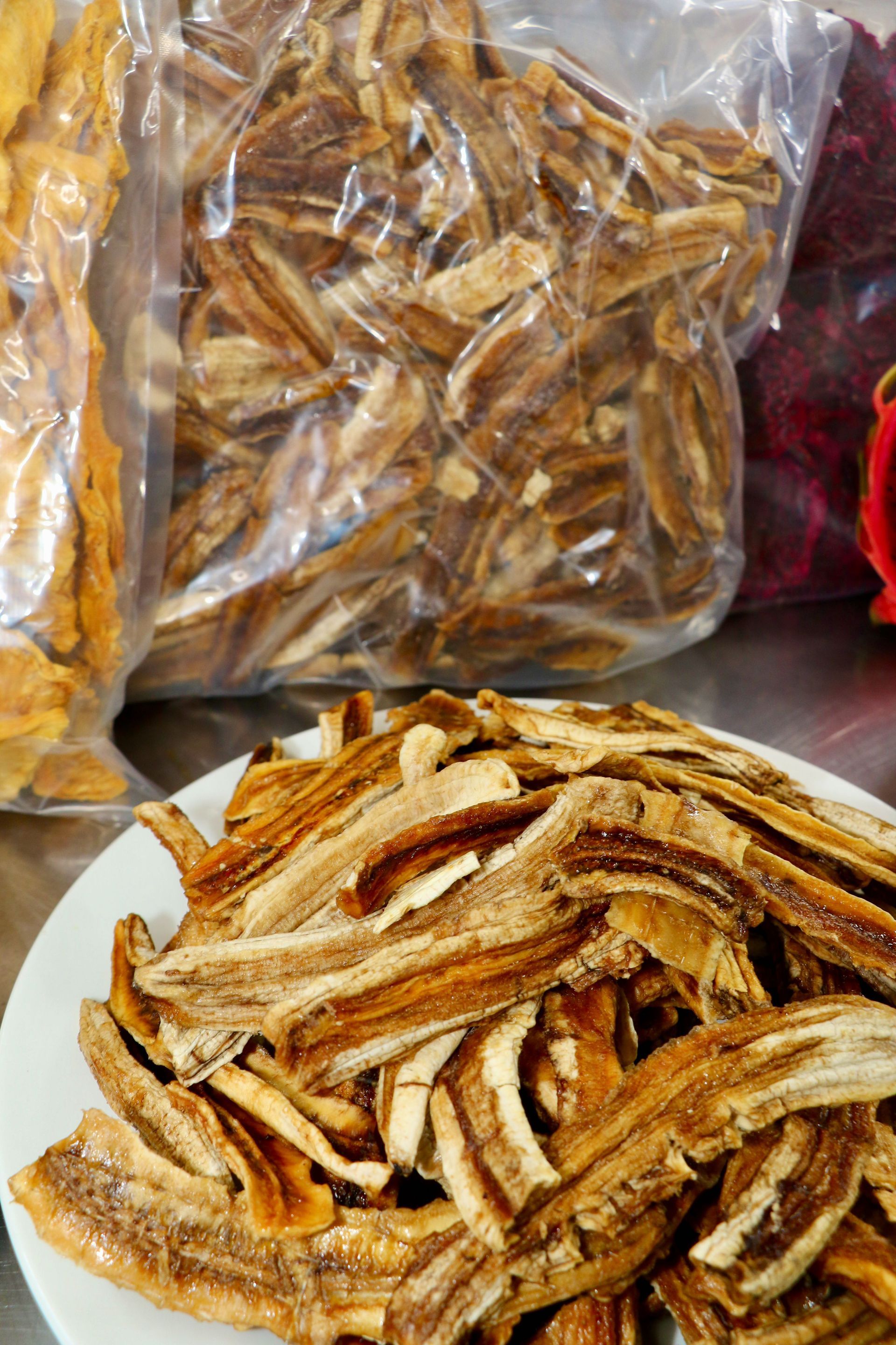 A Plate of Dried Bananas Next to a Bag of Dried Bananas — Mareeba Golden Dried Mangoes in Mareeba, QLD