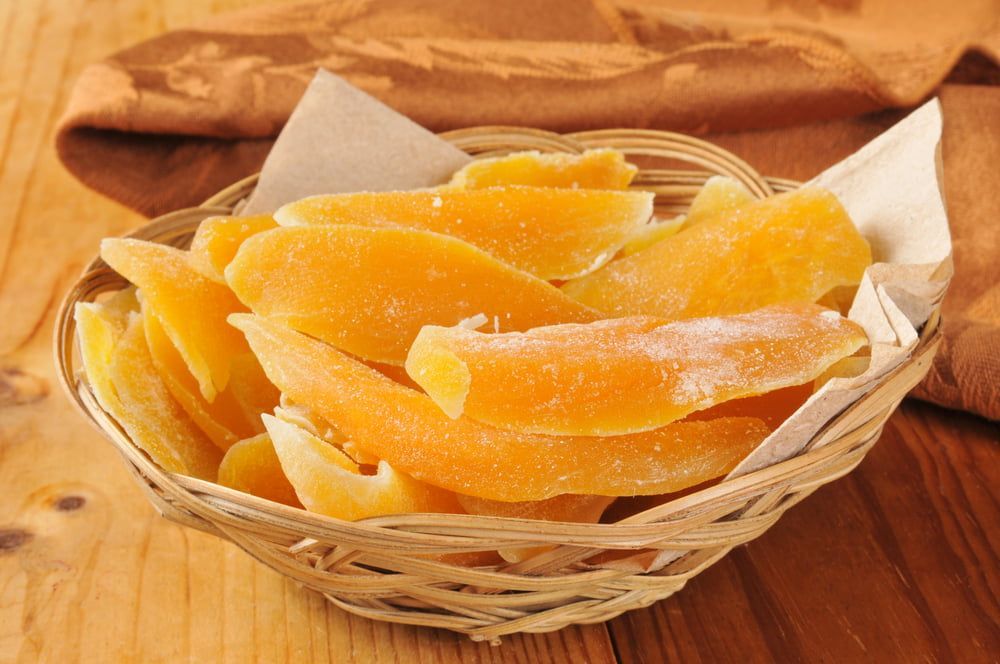 A Basket Filled With Dried Mango Slices on a Wooden Table — Mareeba Golden Dried Mangoes in Cairns, QLD