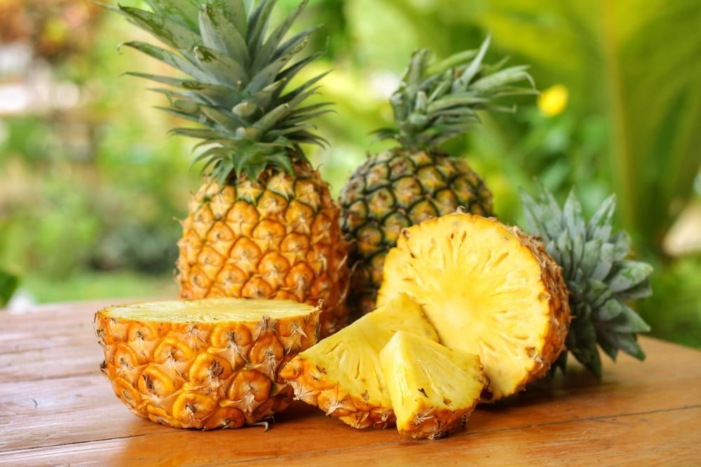 Three Pineapples Are Sitting on a Wooden Table — Mareeba Golden Dried Mangoes in Cairns, QLD