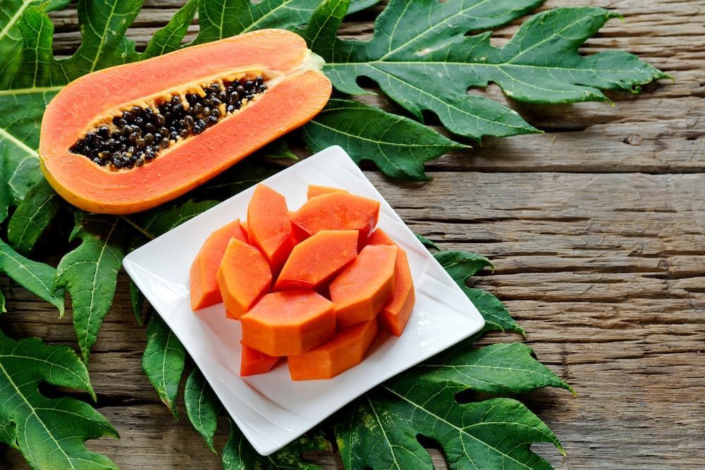 A Papaya Cut in Half and Sliced on a White Plate on a Wooden Table — Mareeba Golden Dried Mangoes in Sunshine Coast, QLD