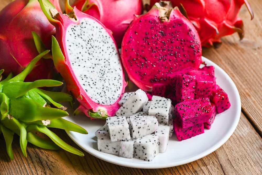 A White Plate Topped With Sliced Dragon Fruit on a Wooden Table — Mareeba Golden Dried Mangoes in Sunshine Coast, QLD