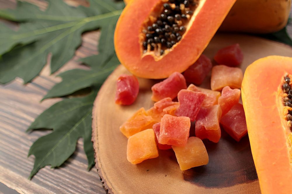 Dried Papaya is Sitting on a Wooden Cutting Board Next to a Papaya — Mareeba Golden Dried Mangoes in Cairns, QLD