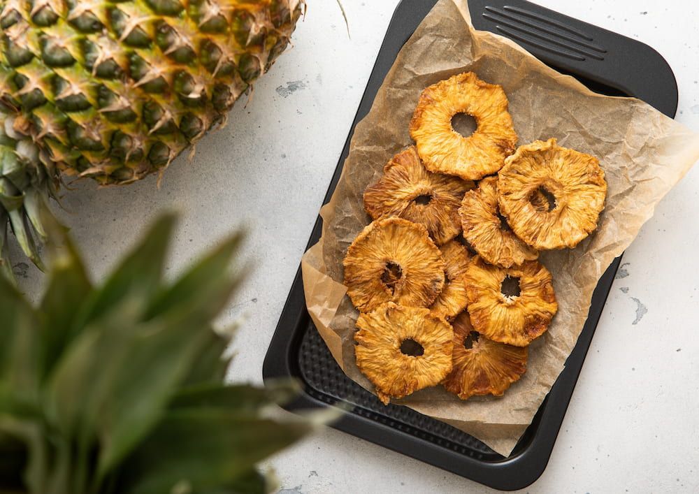A Tray of Pineapple Rings on a Table Next to a Pineapple — Mareeba Golden Dried Mangoes in Gold Coast, QLD
