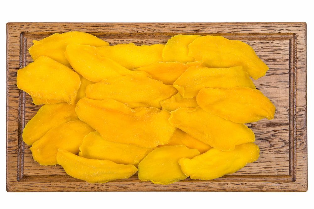 Dried Mango Slices on a Wooden Cutting Board on a White Background — Mareeba Golden Dried Mangoes in Brisbane, QLD