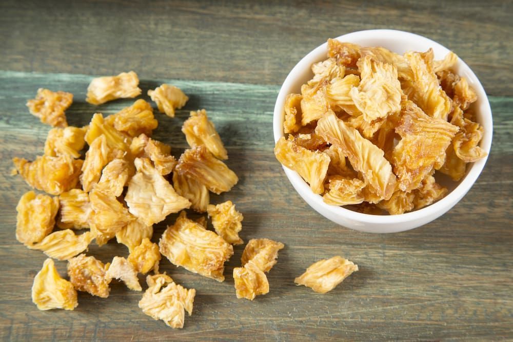 A Bowl of Dried Pineapple Next to a Bowl of Dried Pineapple on a Wooden Table — Mareeba Golden Dried Mangoes in Cairns, QLD