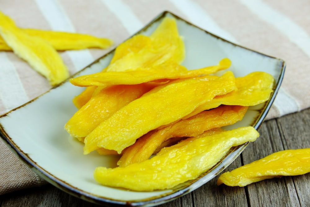 A Bowl of Dried Mango Slices on a Wooden Table — Mareeba Golden Dried Mangoes in Brisbane, QLD