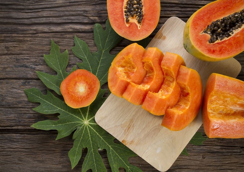 Papaya Slices on a Cutting Board With Leaves on a Wooden Table — Mareeba Golden Dried Mangoes in Brisbane, QLD