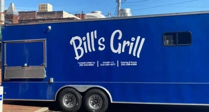 A blue food truck called bill 's grill is parked in front of a building.