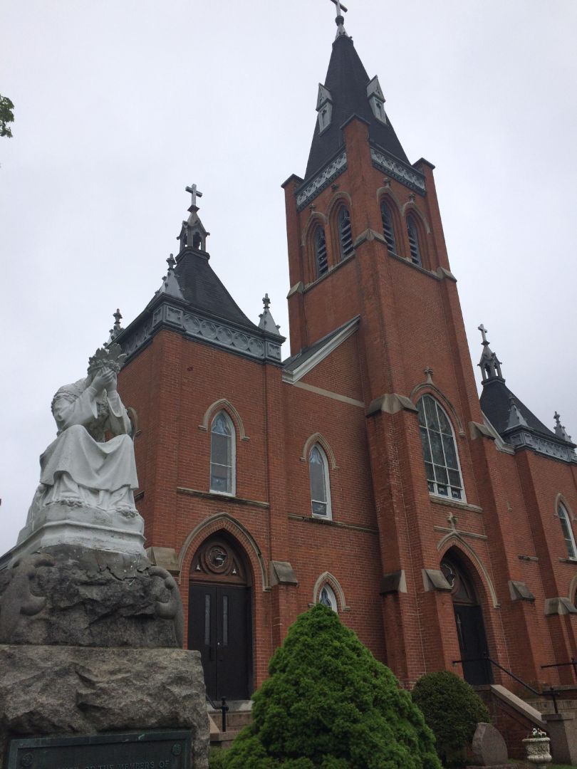 A large brick church with a statue in front of it