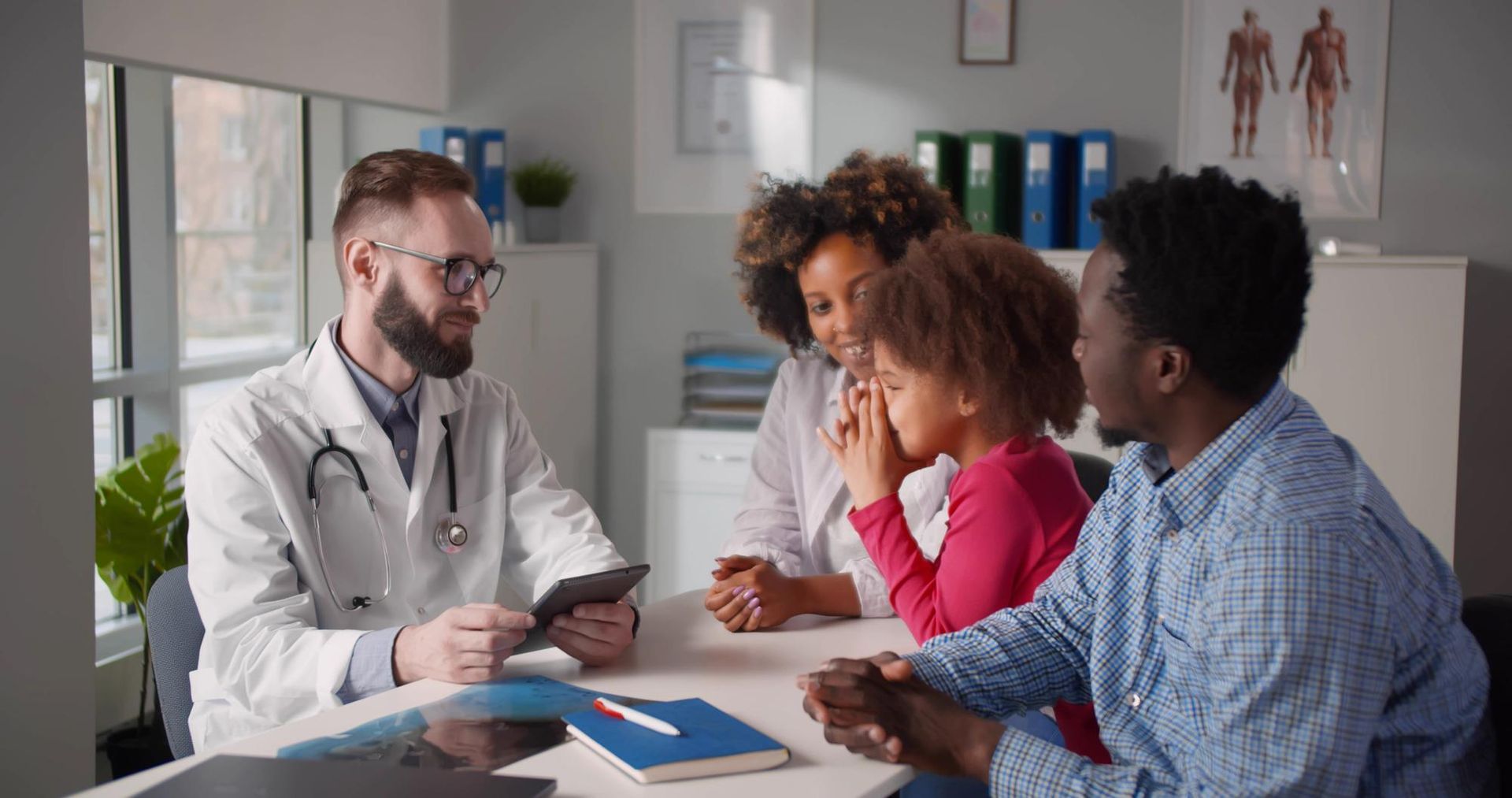 Doctor consulting with three patients around a table in a bright clinic office