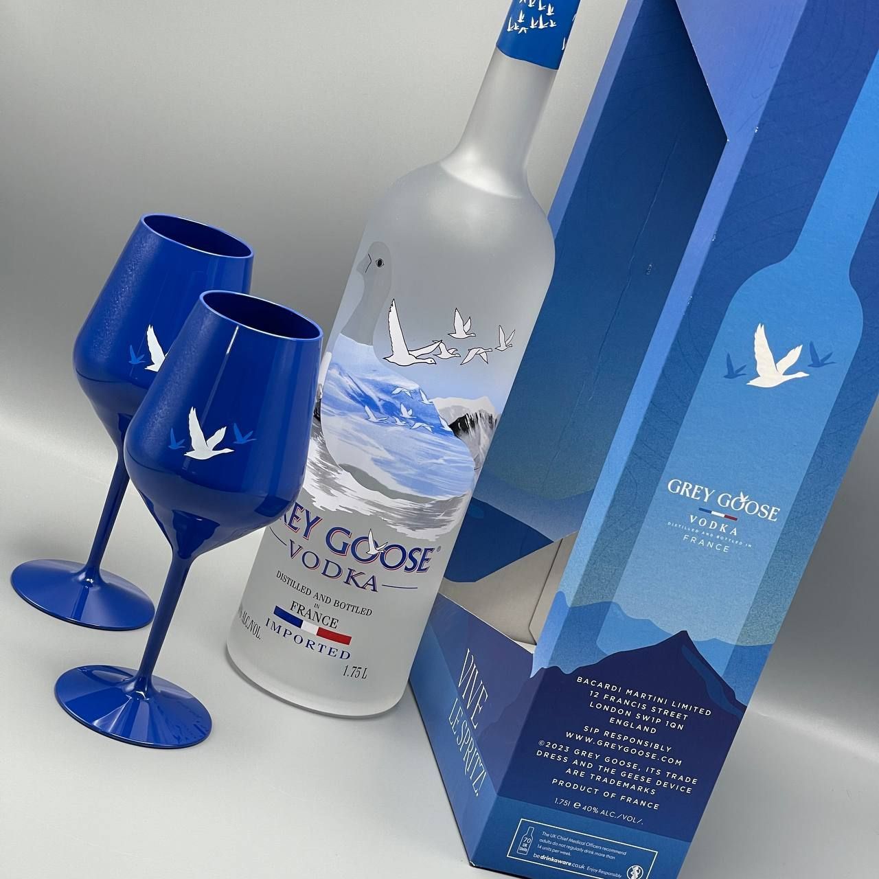 A bottle of grey goose vodka next to two wine glasses