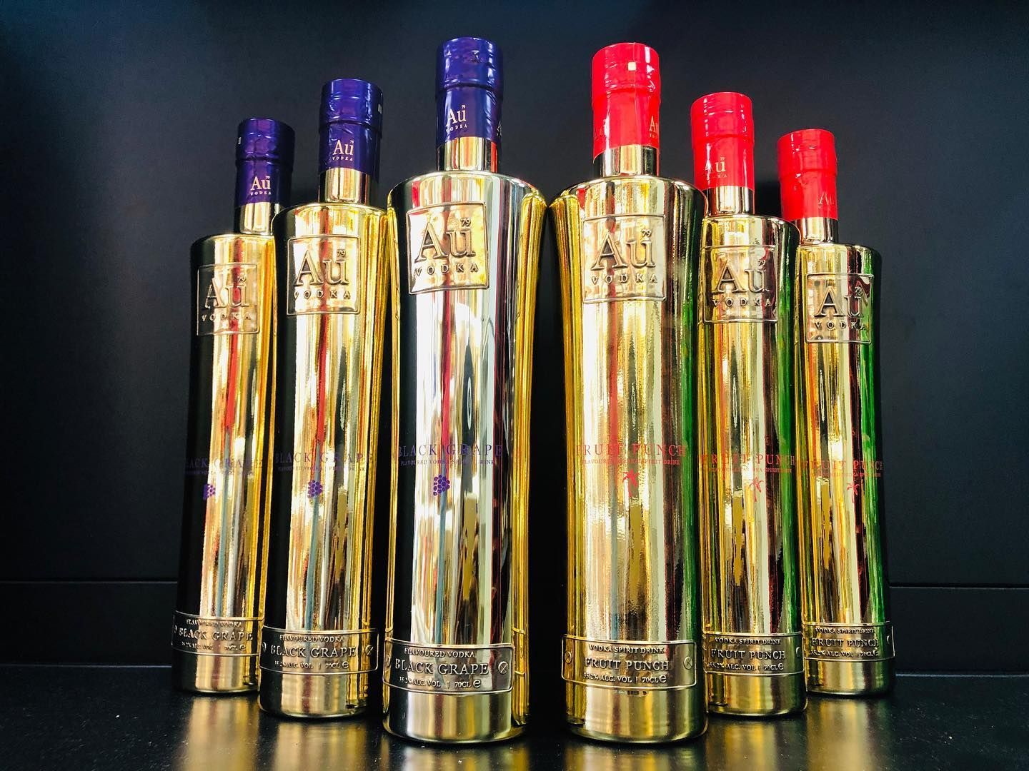 A row of gold colored bottles with red caps