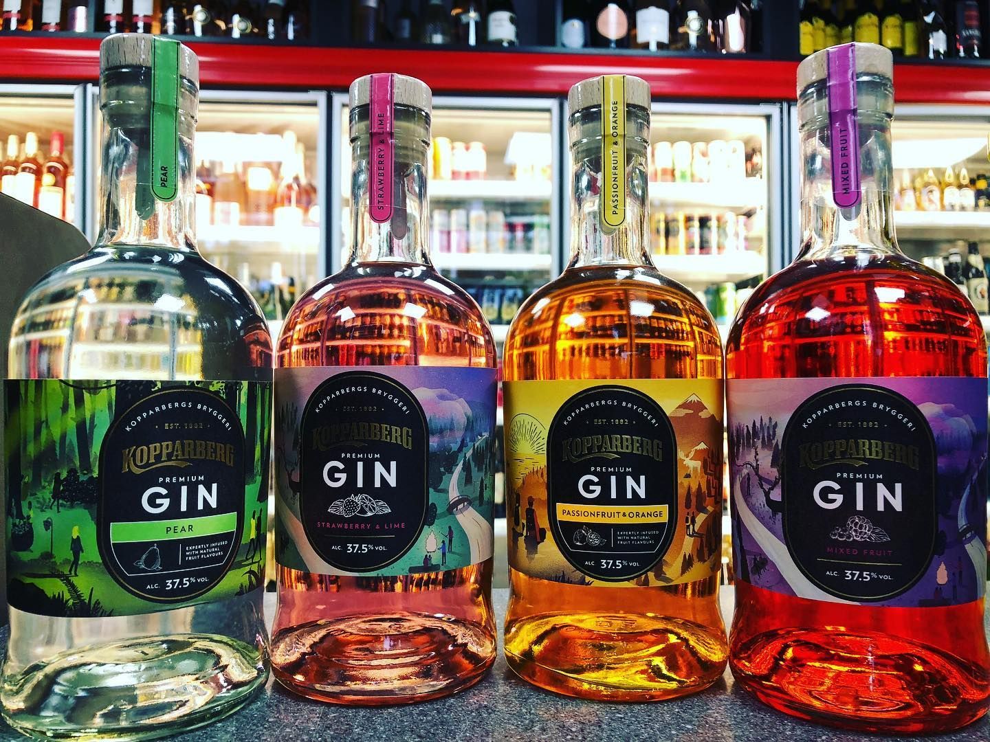 Four bottles of gin are lined up on a counter in a liquor store.