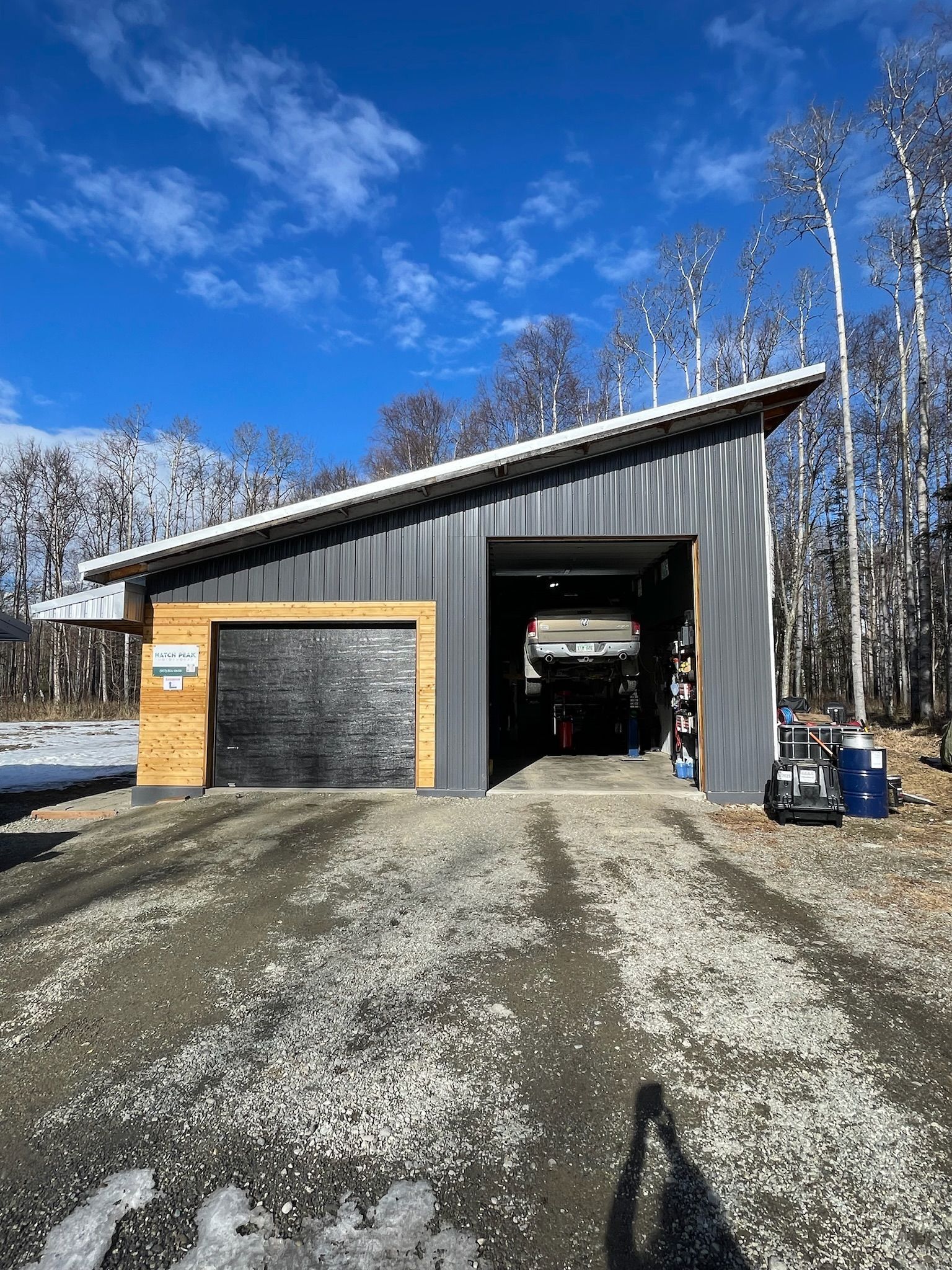 Modern Garage Building Surrounded By Snow And Trees On Sunny Day | Hatch Peak Motorworks