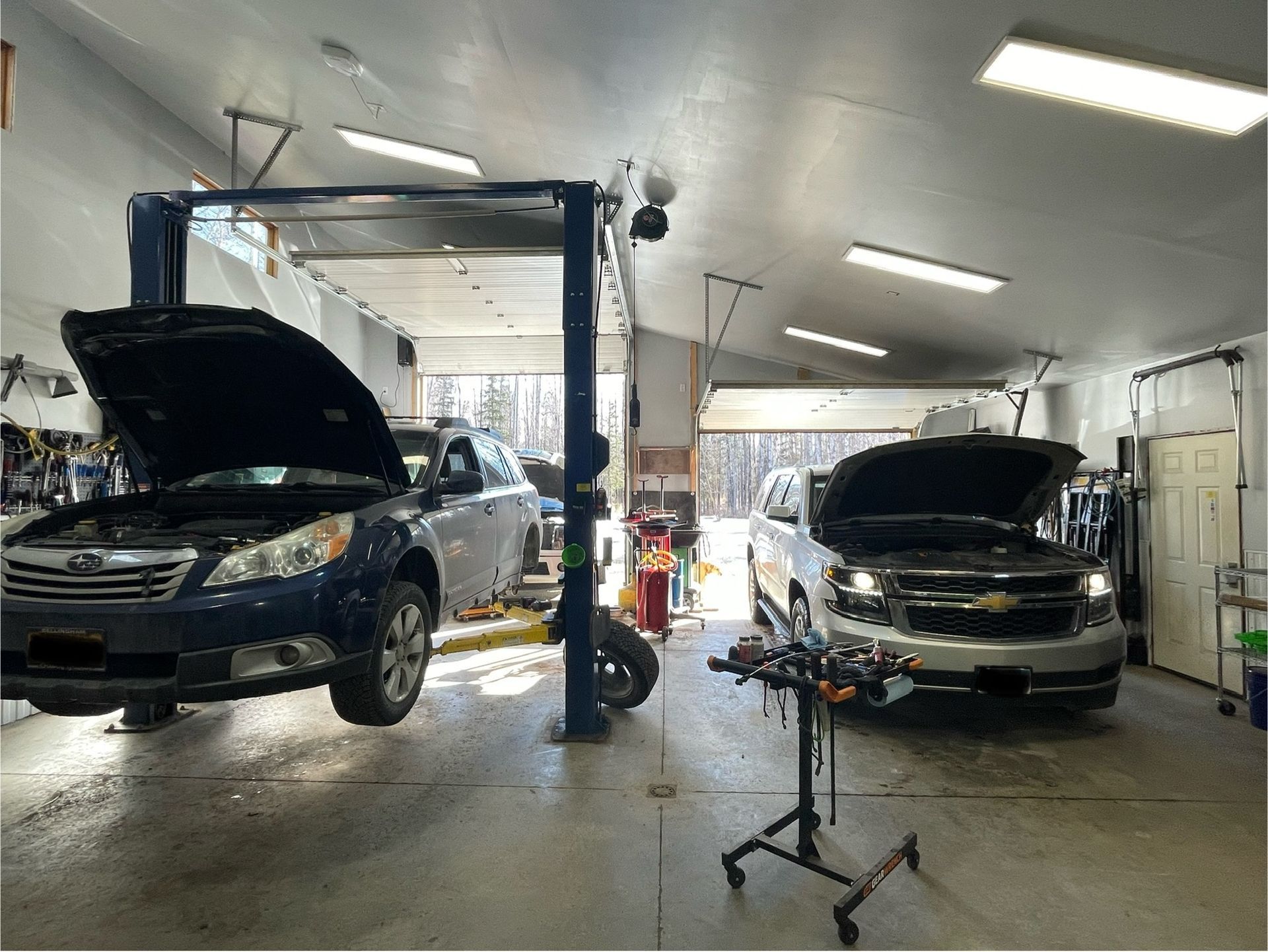 Two Vehicles On Hydraulic Lifts Inside Clean Auto Repair Shop | Hatch Peak Motorworks