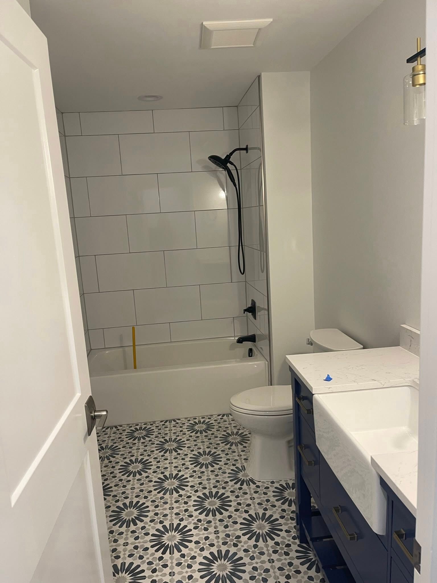 Bathroom with patterned floor tiles, white subway tile shower, and dark vanity.