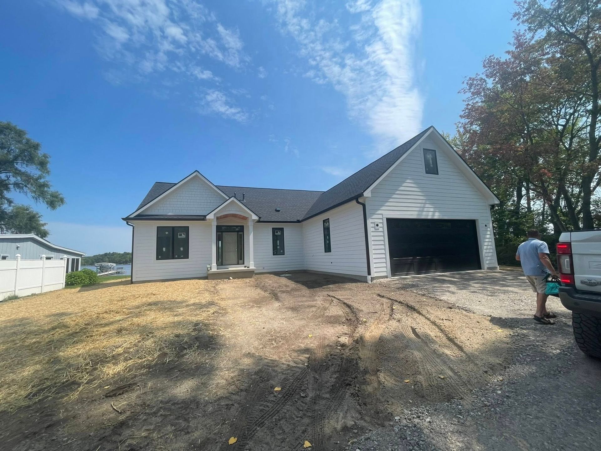 White house with black trim and garage door; man beside a van.