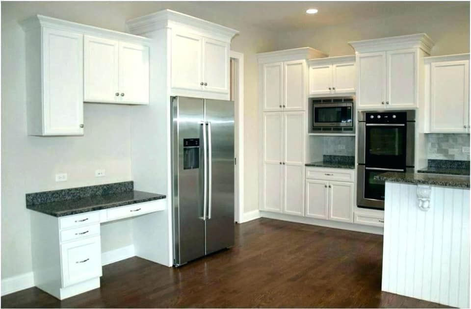 White kitchen with white cabinets, stainless steel refrigerator, and dark countertop.