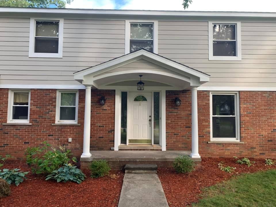 Two-story house with a brick facade on the bottom and light gray siding. White framed windows and a covered entrance.